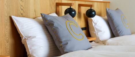 A neatly made bed with white linens and pillows featuring a large 'C' design.