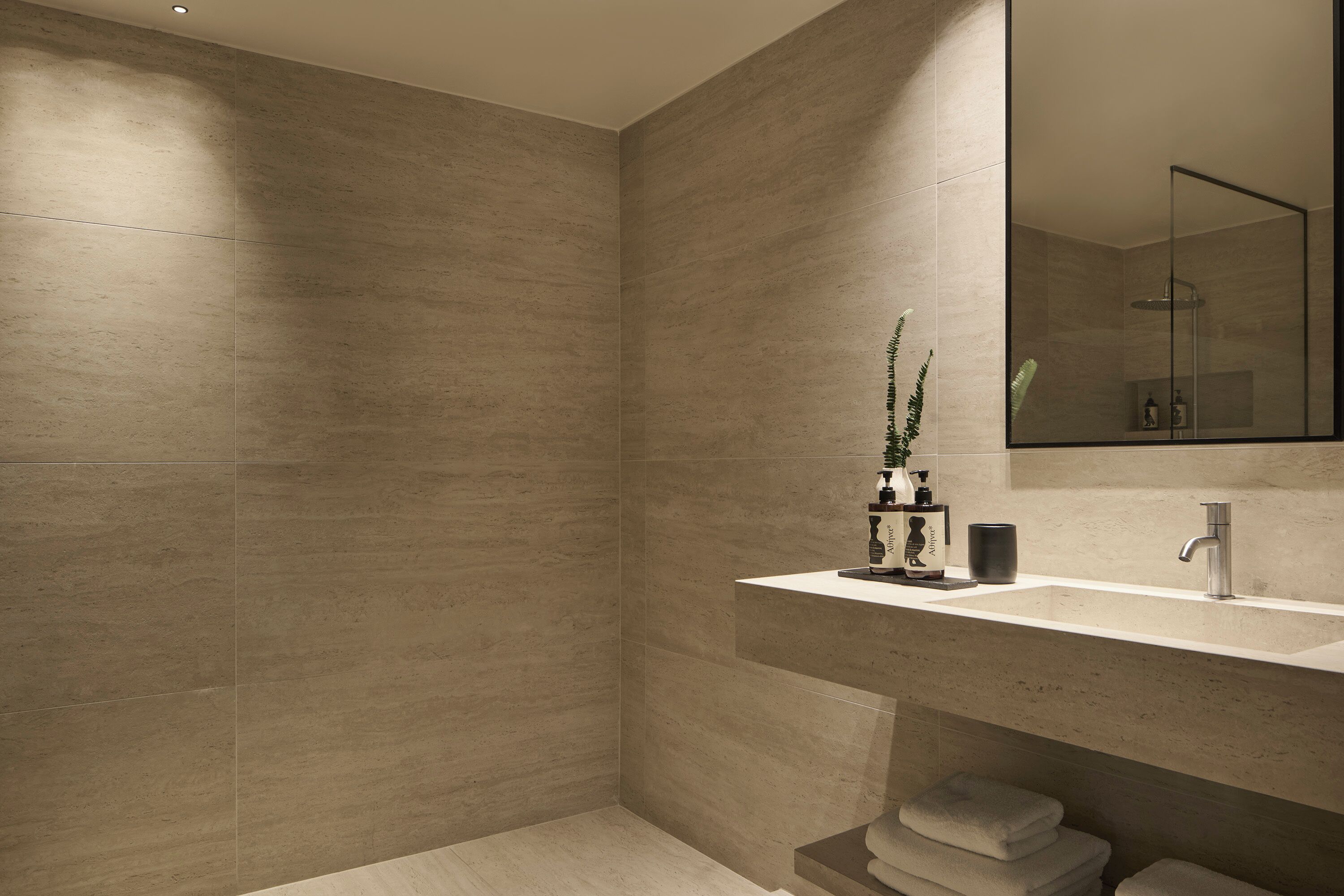 A modern bathroom with a large mirror, a sink, and a shower area.