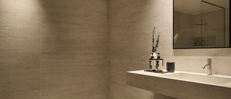 A modern bathroom with a large mirror, a sink, and a shower area.
