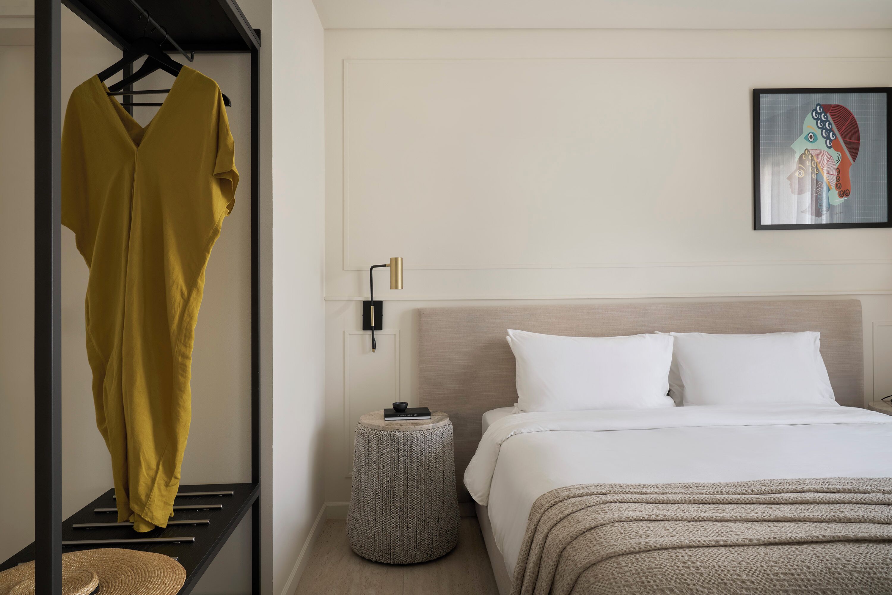 A bedroom with a bed, bedside table, and a hanging garment.