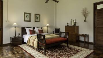 A bedroom with a bed, two chairs, a nightstand, a dresser, and a ceiling fan.