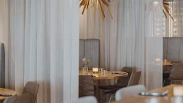 En restauranginteriör med ett runt matbord, stolar och ett ljus som mittpunkt på bordet.