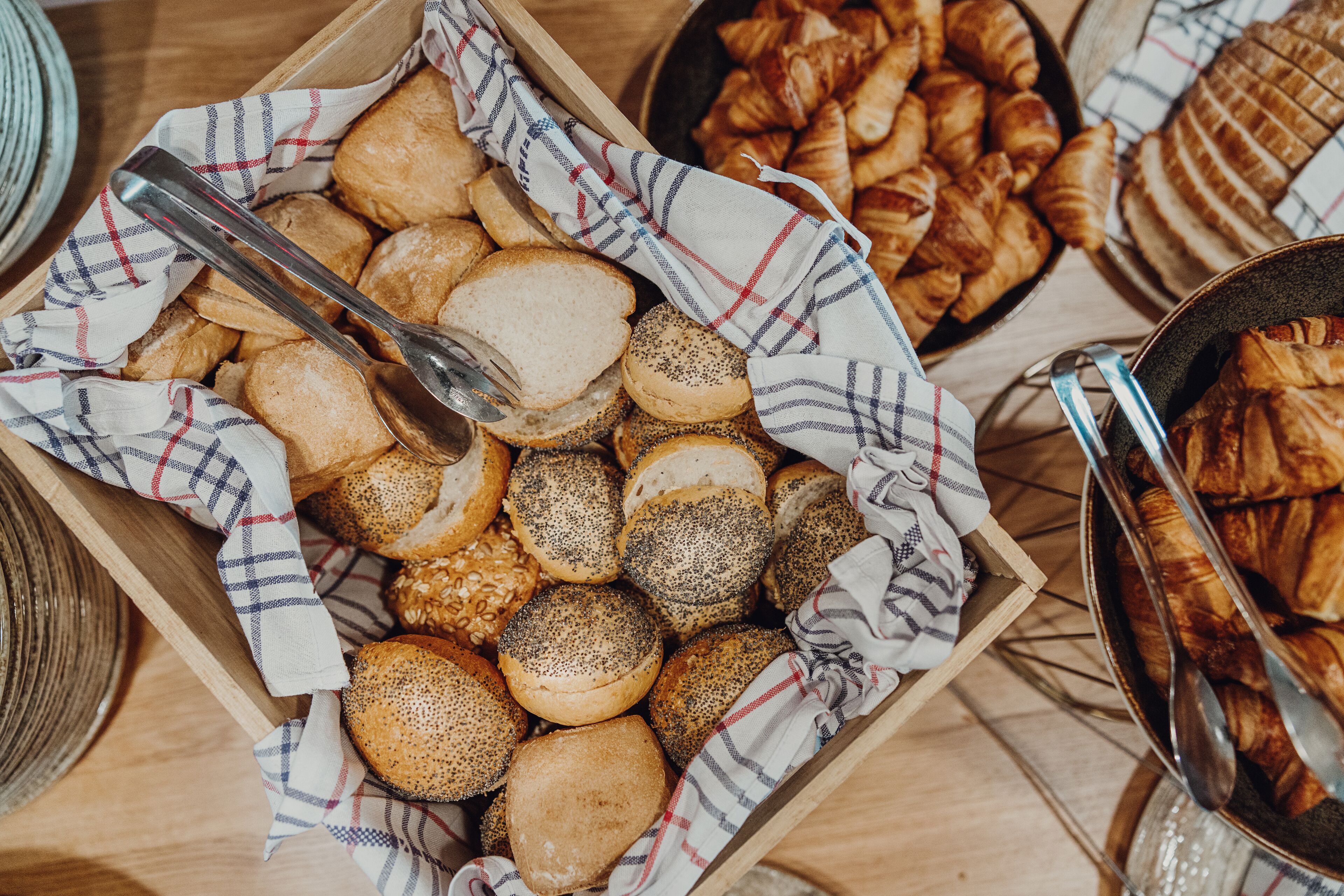 Una variedad de productos horneados, como pan, croissants y pasteles, en una caja de madera.