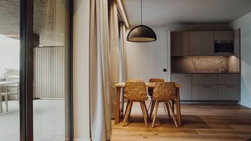 A modern kitchen with wooden cabinets, a dining table with chairs, and a large window with curtains.