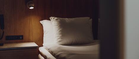 A neatly made bed with white bedding and a wooden headboard.