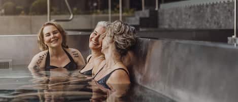 A hot tub area with a metal railing and a view of a building in the background.