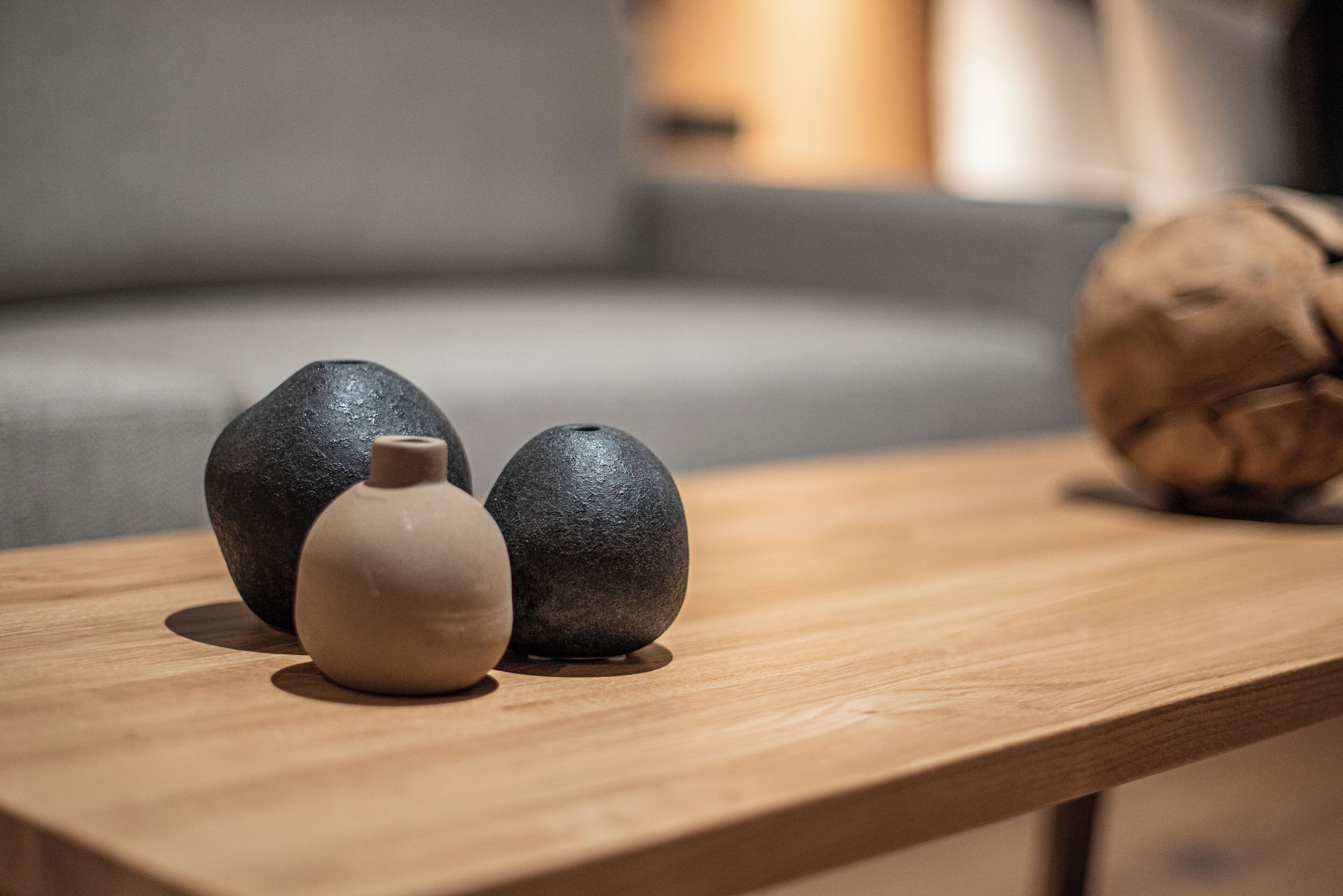 Una mesa de madera con tres piedras y un pequeño florero.