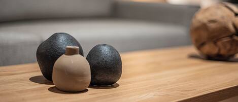A wooden table with three stones and a small vase.