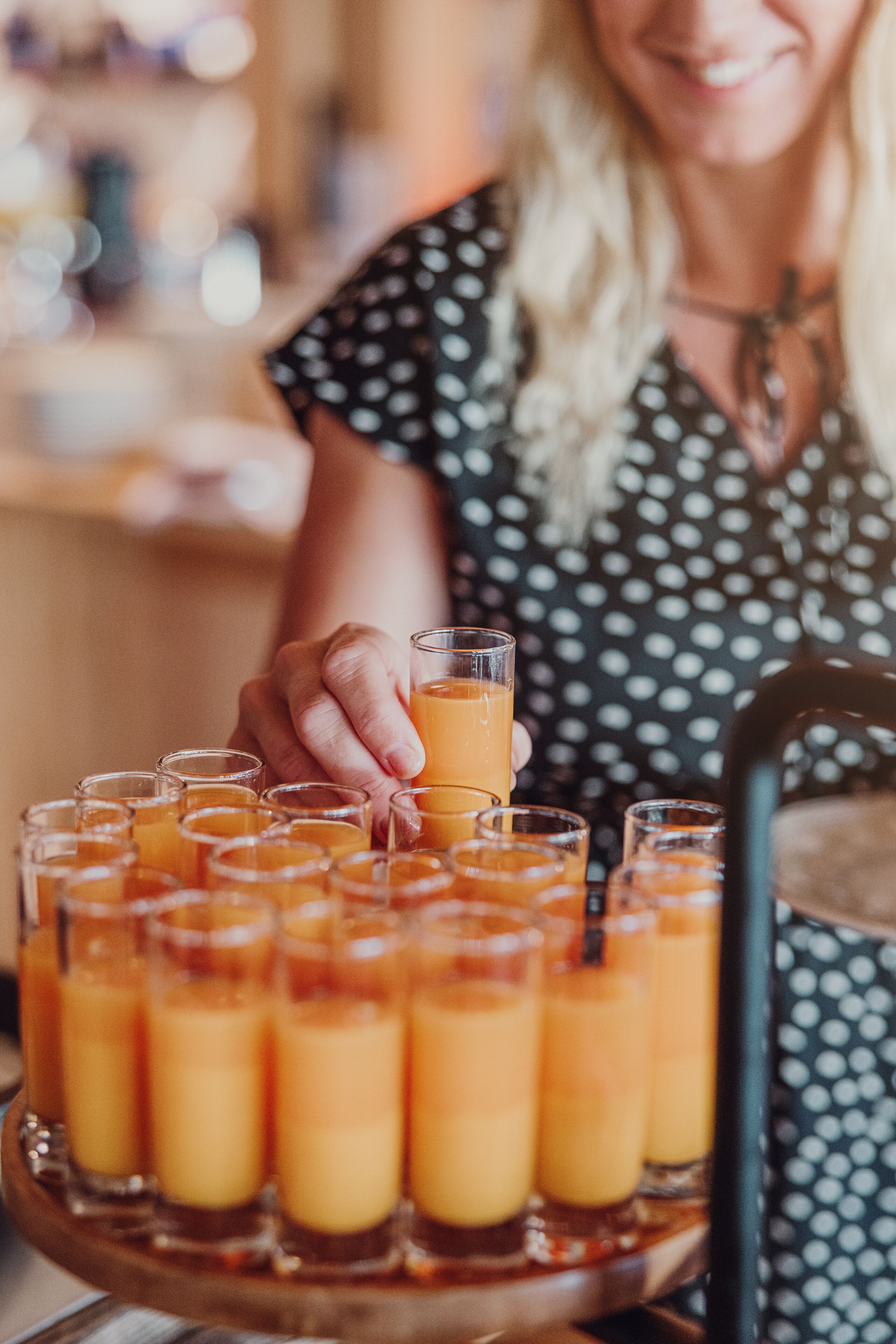 A tray of orange juice glasses arranged on a wooden stand.