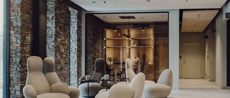 A modern lobby with unique sculptural chairs, a stone wall, and a wooden shelving unit.