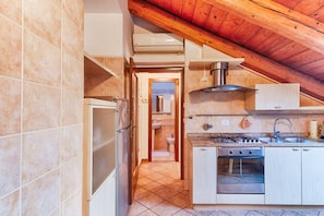 A kitchen with a stove, oven, and sink, a hallway leading to a bathroom, and a wooden ceiling. - GuestHost - Apartment located on the fifth floor of a building with a lift (there are 10 internal steps at the entrance to the apartment).In 45 sqm it comfortably accommodates 3 people, with a bedroom with two single beds and a sofa bed.Convenientlyt loc (Trieste)