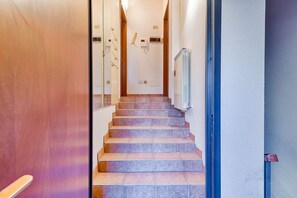 A staircase leading to a room with a white door, a wall-mounted light fixture, and a radiator.