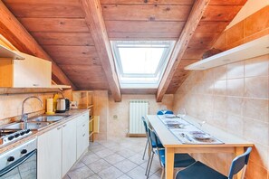 A compact kitchen with a skylight, a dining table with chairs, and a radiator.
