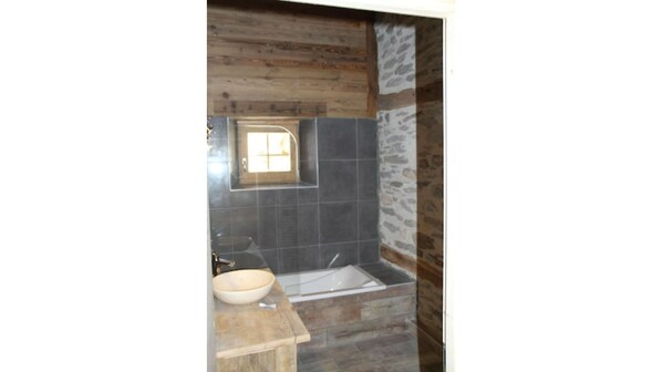 A bathroom with a wooden wall, a stone accent wall, a sink, and a bathtub. - Pont de l'arc, La Villarine (Val-Cenis)