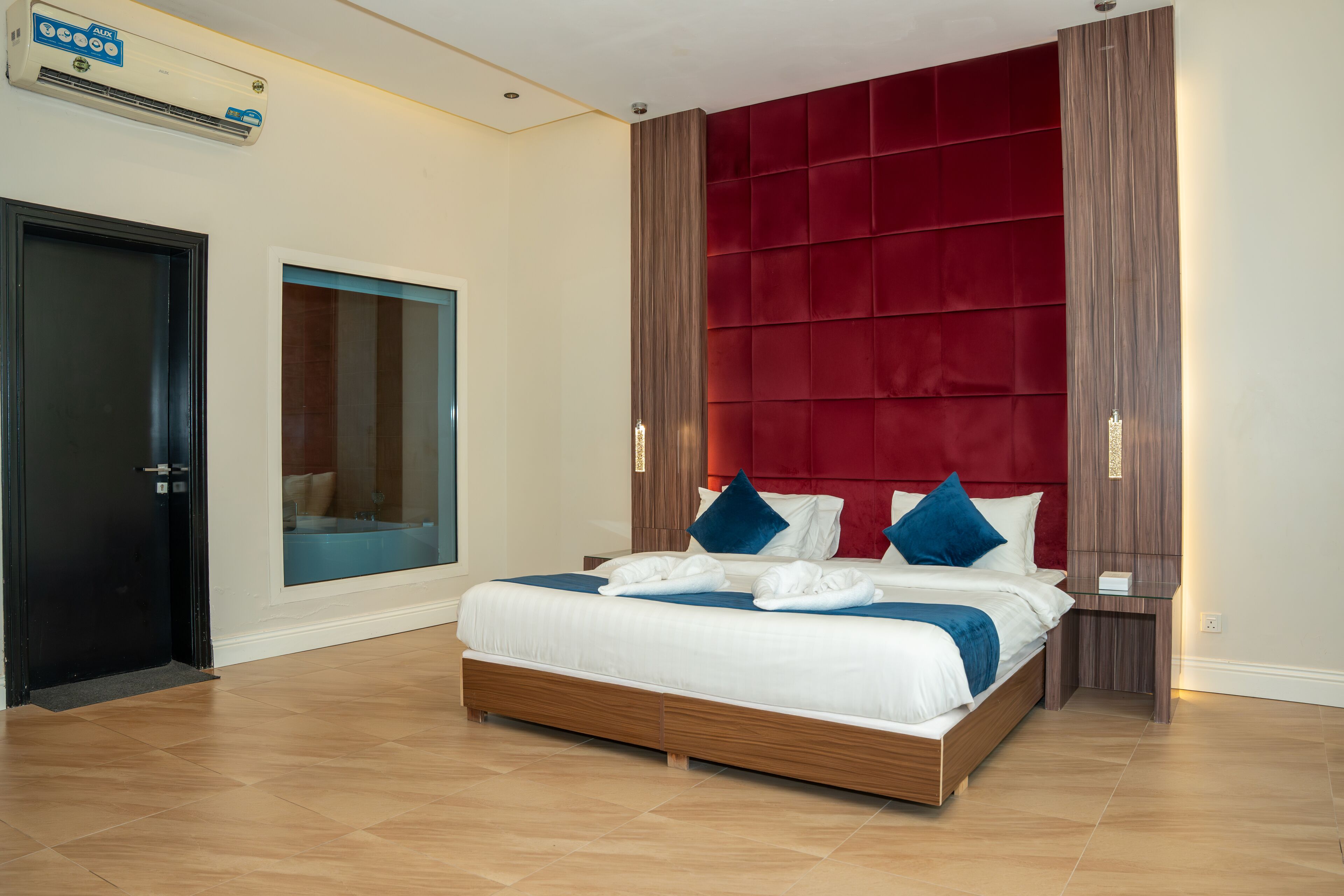 Een moderne hotelkamer met een groot bed, een rode hoofdbord en een glazen deur.