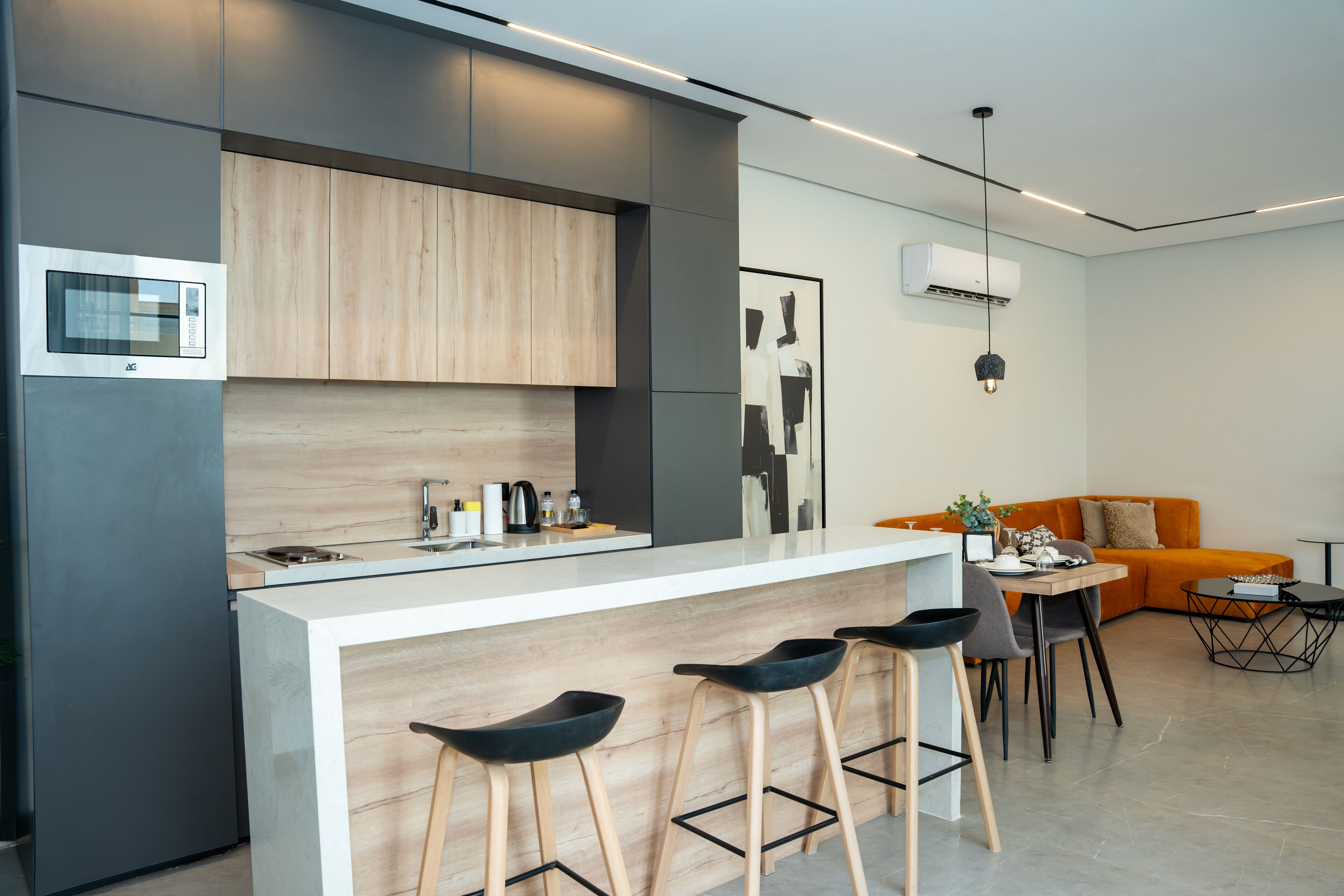 Een moderne keuken met een centraal eiland, barkrukken en een zithoek met een bank en salontafel.