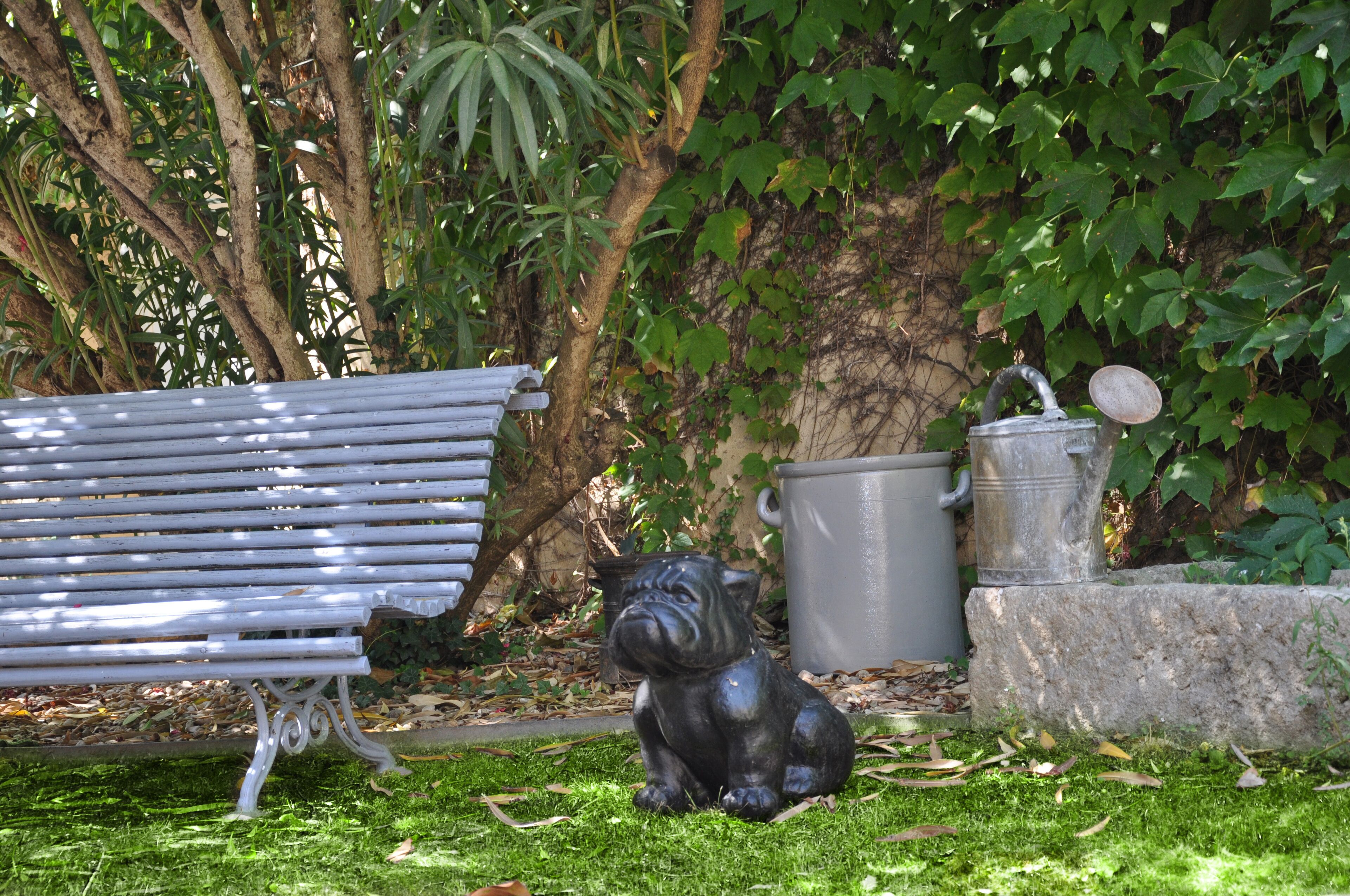 Eine Parkbank, ein Metallmülleimer und eine Bulldog-Statue.