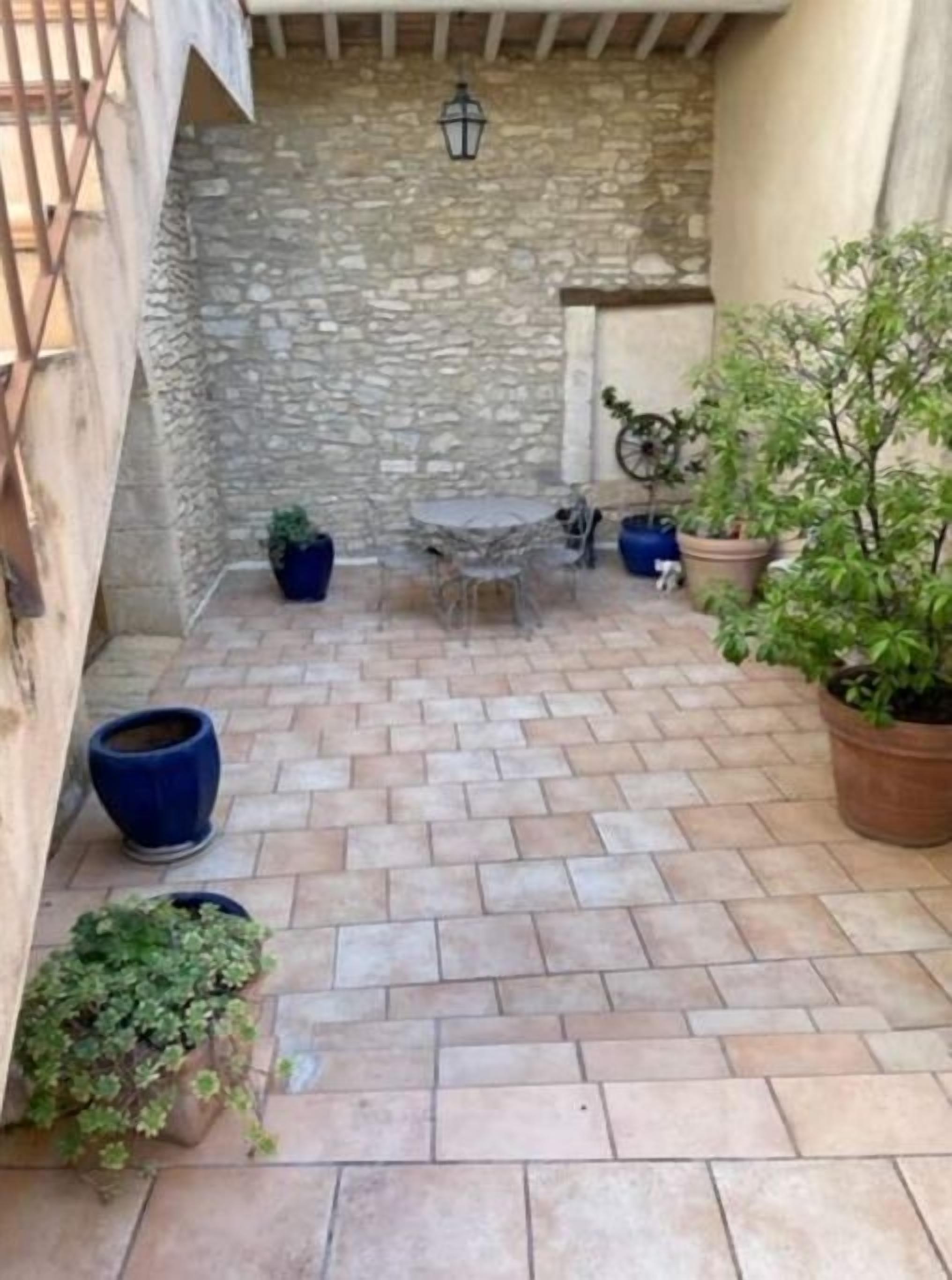 A stone-walled patio with a tiled floor, outdoor furniture, and potted plants.