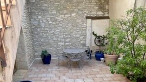 A stone-walled patio with a tiled floor, outdoor furniture, and potted plants.