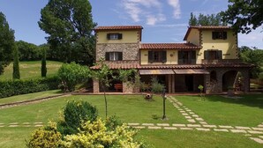 A two-story house with a stone facade, a tiled roof, and a well-maintained lawn.