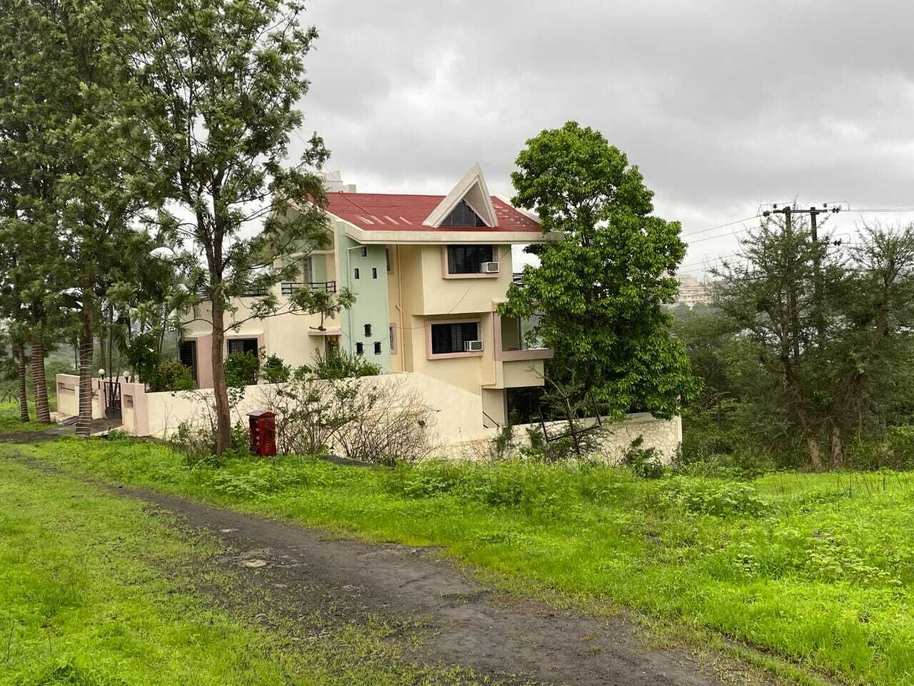 Un edificio de dos pisos con techo rojo, rodeado de vegetación y árboles.