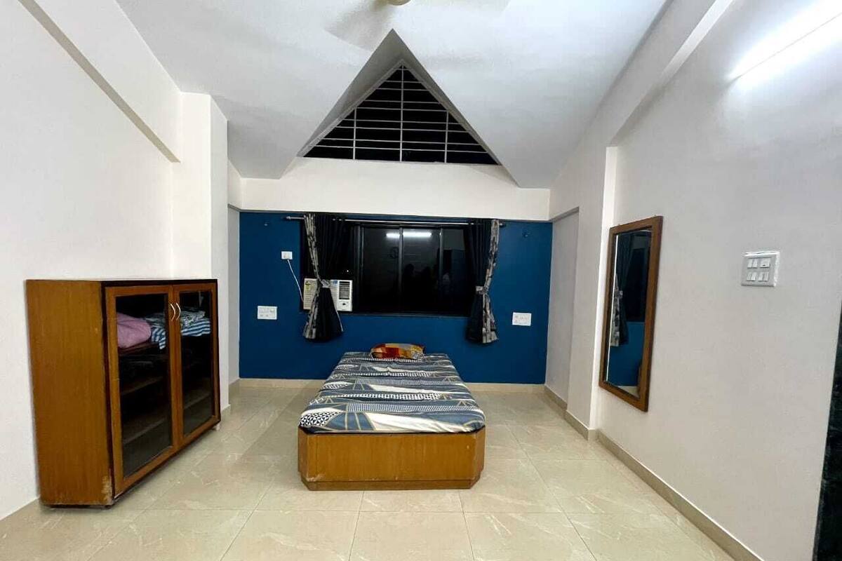 A bedroom with a bed, wardrobe, and a mirror.