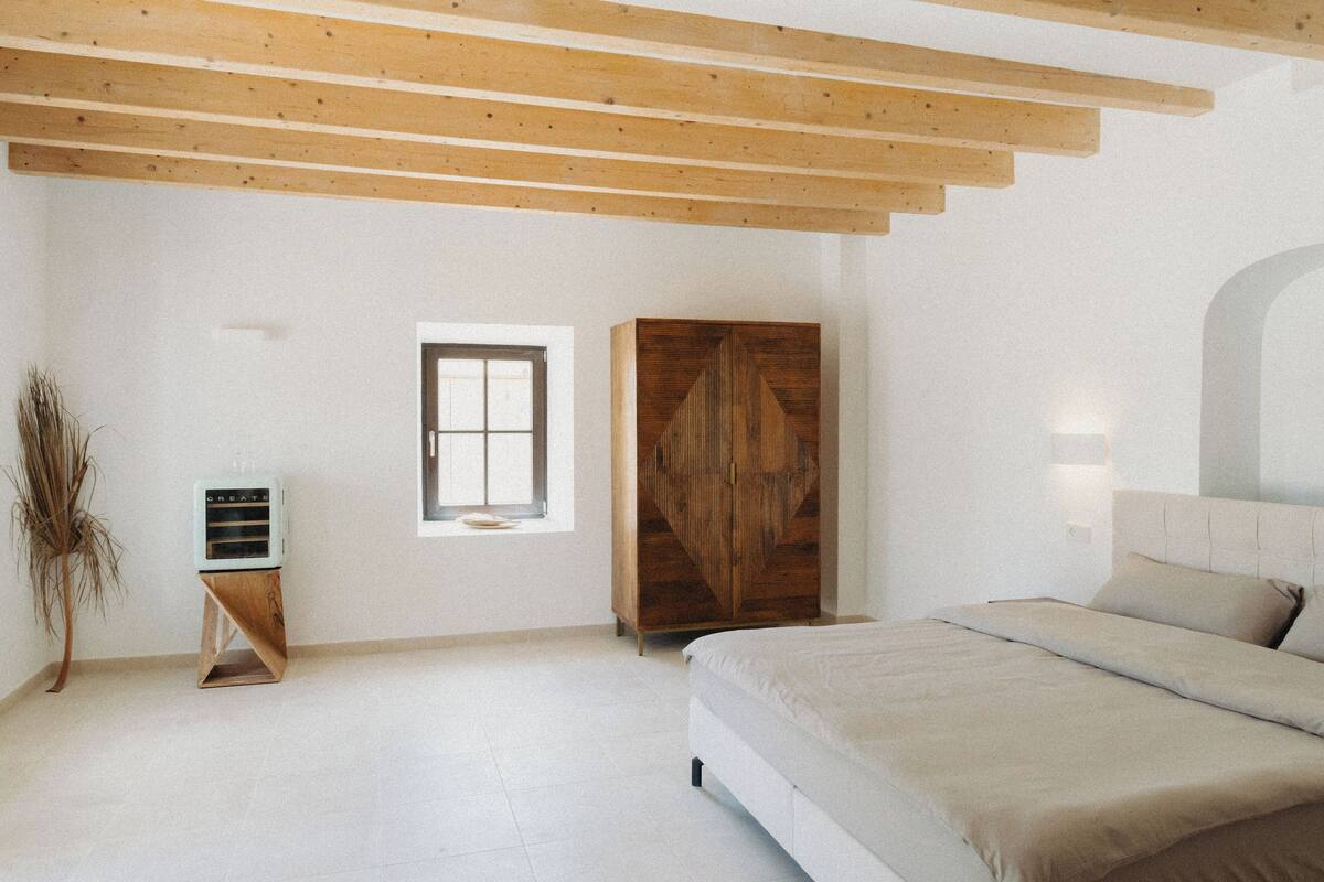 A bedroom with a bed, a wardrobe, a window, and a radiator.