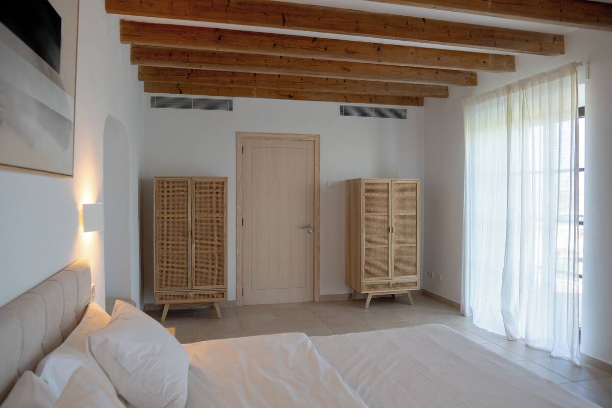 A bedroom with a bed, wooden wardrobe, and a door.