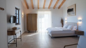 Un dormitorio con cama, mesitas de noche, televisor y ventana con cortinas.