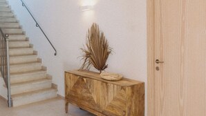 Una escalera con barandilla de madera, un armario de madera con objetos decorativos, y una puerta sencilla.