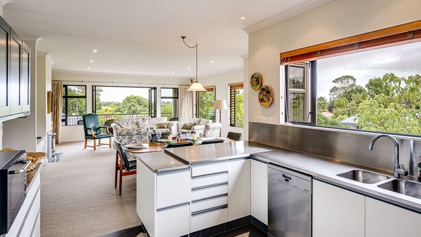 A modern kitchen with a central island, stainless steel appliances, and a large window overlooking greenery. - Busby Hill Villa - Havelock North Holiday Home (Havelock North)