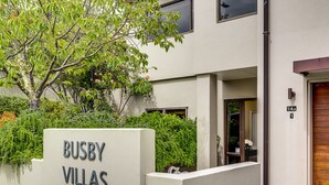 A modern building with a sign reading "BUSBY VILLAS" and a gated entrance. - Busby Hill Villa - Havelock North Holiday Home (Havelock North)