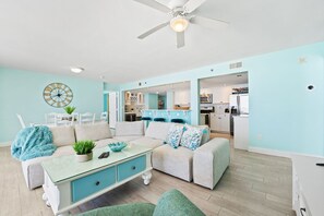 A modern living room with a sofa, a glass coffee table, and a dining area with chairs.