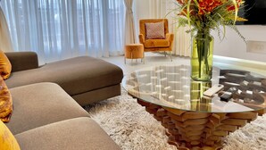 A modern living room with a sofa, a round glass coffee table, and a TV.
