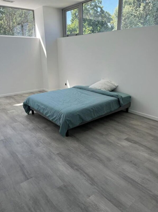Cozy retreat with a single bed positioned against a wall, featuring a large window and neutral-toned walls.