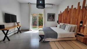 A modern bedroom with a large bed, a TV, and a wooden accent wall. - Villa Cactus, 5 Chambres, Piscine Chaufée (Marrakech)