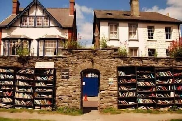 A building with a stone facade, a blue door, and bookshelves on either side.