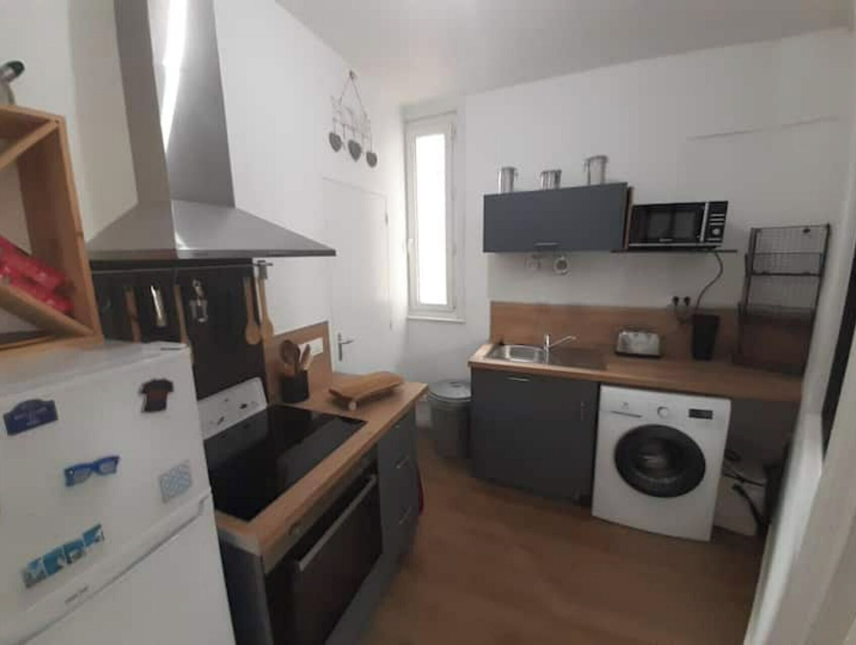 A compact kitchen with a refrigerator, microwave, sink, and washing machine.