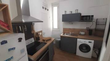 A compact kitchen with a refrigerator, microwave, sink, and washing machine.