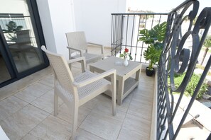 A balcony with two wicker chairs, a small table, a potted plant, and a metal railing. - Downtown Tunis Hotel (Tunis)