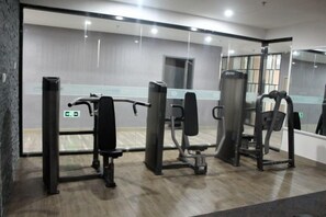 A gym with exercise equipment, a mirror, and a wooden floor.