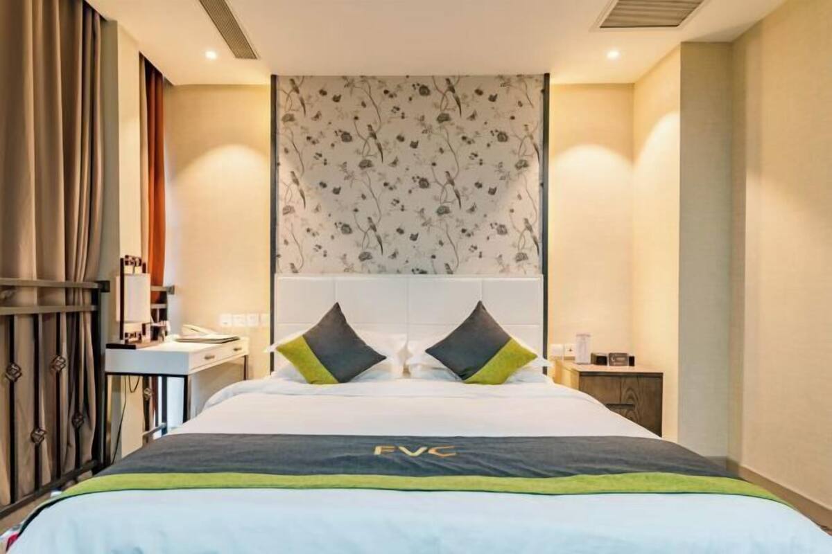 A hotel room with a bed, a desk, and a nightstand.