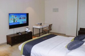 A hotel room with a bed, a desk, a chair, a television, and a dresser. - Food Valley Hotel (Weifang)