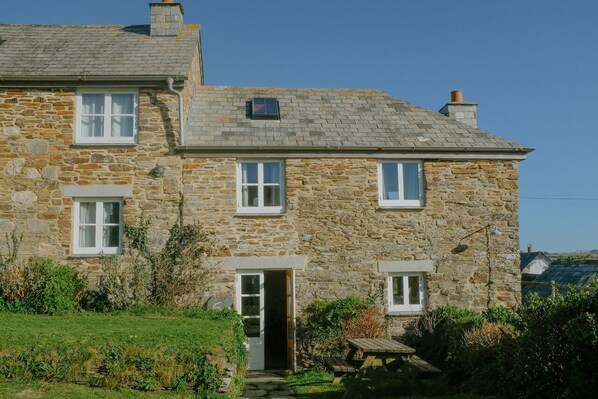A stone house with a sloped roof, multiple windows, and a small front porch. - Cosy cottage, peaceful setting 5 mins to beautiful sandy beach & fabulous walks! (Mawgan Porth, Cornwall)