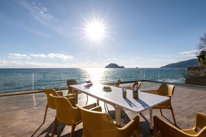 Ett utomhusområde med plats för att äta, med utsikt över havet och bergen.