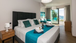 A hotel room with a large bed, a nightstand, a lamp, a window with a view of the sea, and a chair by the window. - MaDiZé Beach House on the Sea (Zakynthos)