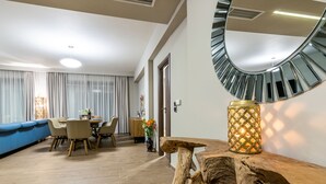 A modern living room with a dining area, featuring a wooden coffee table, a blue sofa, and a large mirror on the wall. - MaDiZé Beach House on the Sea (Zakynthos)