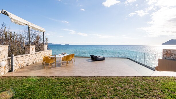An outdoor patio with a table and chairs, a bean bag, and a view of the sea. - MaDiZé Beach House on the Sea (Zakynthos)