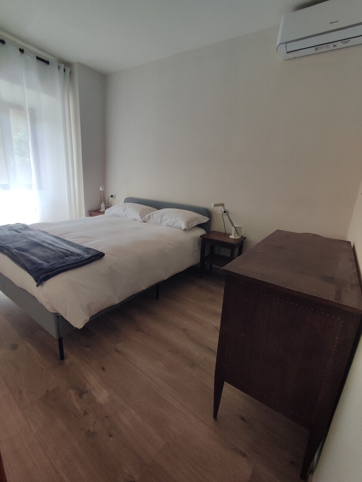 Una camera da letto con un letto, comodini, una scrivania e un condizionatore d'aria.