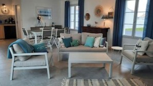 A modern living room with a sofa, armchairs, a coffee table, and a dining area with a table and chairs. - Magnifique Villa St Denis D'oléron (Saint-Denis-d'Oléron)